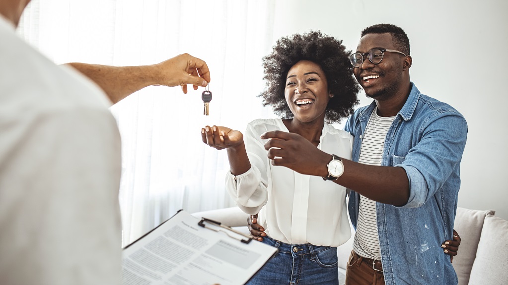 Couple Getting Keys From Realtor Of Their New Home. Portrait of financial adviser congratulating to a young couple for buying a new house. African-American  family buy new house